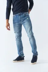 Pantalón jean de calce regular, color celeste con efecto lavado y roturas.