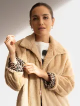 Tapado negro de piel sintética con cuello solapa y mangas largas. El forro interior de las mangas tiene un estampado animal print.