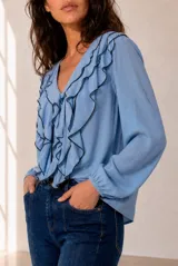 Blusa celeste de manga larga con escote en V y volados en cascada ribeteados en color oscuro. Cuenta con puños elásticos.
