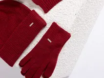 Set de accesorios de invierno en color beige melange, compuesto por un gorro tipo beanie de punto acanalado, un par de guantes de punto y una bufanda de punto con terminación acanalada.