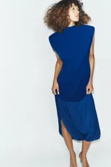 Vestido midi de color azul eléctrico con cuello subido y diseño sin mangas. Presenta un cuerpo liso y una falda con caída fluida y detalle de tul en el bajo.