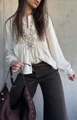 Camisa de lino color natural, con calce relajado, mangas largas amplias con puños fruncidos y delicado bordado geométrico en el frente.