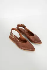 Sandalia chata color marrón con textura tejida, punta fina y tira trasera con hebilla dorada.