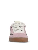 Championes de estilo urbano en color lila, confeccionados en material sintético con textura similar a la gamuza. Presentan detalles en color marrón oscuro en la puntera y el talón, cordones claros y suela de goma color caramelo.