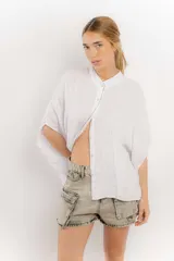 Camisa color crema de lino con mangas amplias y cinta en tono más oscuro en el cuello y la botonadura.