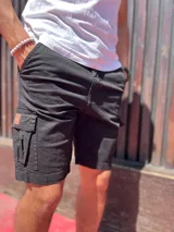 Bermuda cargo de gabardina en color azul marino, con bolsillos laterales con solapa y detalle de etiqueta de cuero sintético.