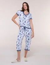 Conjunto pijama de pantalón capri y remera René Rofé, de color blanco con estampado floral en tonos azules y celestes. Remera de manga corta con escote en V y detalles de encaje azul en el escote, las mangas y el ruedo. Pantalón capri con cintura elastizada, cordón de ajuste y encaje en el ruedo.