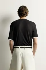 Remera relaxed fit confeccionada en tejido ligero de lyocell, de color negro con cuello redondo, manga corta y acabados en efecto doble combinado a contraste en color blanco.