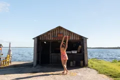 Vestido corto con escote en V y breteles finos, confeccionado en una mezcla de lino y algodón. Presenta un estampado floral vibrante en tonos naranja, rosa y blanco, con un corte relajado que se ajusta suavemente al cuerpo y un pequeño tajo lateral en el ruedo.