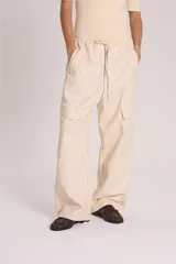 Pantalón babucha color crema de cuero sintético, tipo cargo, con cintura elastizada y lazo de ajuste.