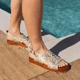 Sandalias de cuero color blanco con textura tipo reptil, plataforma marrón y hebilla metálica plateada.