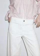 Jeans estilo wide leg de tiro alto en color blanco, con bolsillos de parche delanteros y cierre de cremallera y botón.