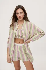 Camisa oversize de manga larga con estampado de rayas verticales en tonos rosado, celeste y verde menta. Cuenta con cuello camisero, cierre frontal con botones y un bolsillo aplicado en el pecho.