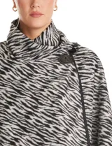 Ruana de Jones New York con estampado animal print en tonos blanco y negro. Presenta un diseño envolvente con cuello alto y cierre frontal mediante un botón tipo trenca.