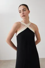 Maxi vestido negro con escote halter cruzado en color crema.