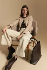 Cárdigan beige de manga larga, tejido liviano y suave, con volados en el delantero, ruedo y puños. Cierre frontal con botones.