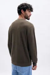 Buzo de tejido de punto color marrón oscuro, con cuello redondo y manga larga. Presenta una textura acanalada vertical.