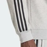 Buzo Adidas 3S Crew color gris melange, con cuello redondo, mangas raglán y las tres tiras características de la marca en negro a lo largo de las mangas. Incluye el logo del trébol bordado en el pecho.