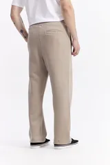 Pantalón de algodón de corte recto y estilo relajado, color beige. Cuenta con cintura elástica con cordón de ajuste, bolsillos laterales y logo de la marca estampado discretamente en el frente.