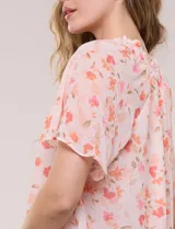 Blusa blanca de doble capa de gasa con estampado floral en tonos amarillos, celestes y rosados, escote en V con frunces y mangas cortas con volados amplios.