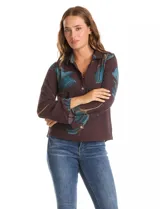 Camisa de crepe marca ABS Allen Schwartz, color marrón con estampado de hojas en tonos verdes y azules. Presenta cuello con solapa, cierre frontal con botones, mangas largas anchas y detalle de bordado con mostacillas en los hombros.