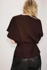 Chaqueta marrón de punto con cuello redondo y manga corta. Presenta cierre frontal con botones y un cinturón integrado del mismo tejido con lazo para atar en la cintura.