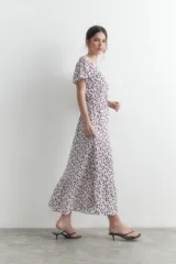 Maxi vestido blanco con estampado floral en tonos violeta, de manga corta y corte evasé.