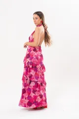 Vestido largo fucsia con estampado abstracto, cuello halter con abertura en forma de lágrima y volados en la falda.