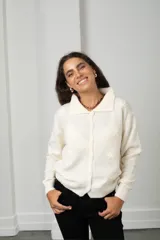 Saco tejido de punto color blanco, con cuello tipo polo, cierre frontal con botones y diseño con flores bordadas en relieve.