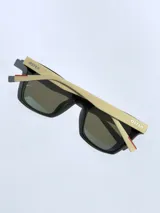 Lentes de sol con armazón bicolor, frente negro y patillas en tono beige con detalle de marca grabado. Cuentan con cristales polarizados con protección UV 400.