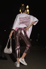 Pantalón de ecocuero con acabado metalizado en color rosado, de corte capri semi oxford y tiro medio-alto. Presenta cierre frontal con botón metálico y bolsillos traseros.