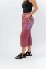 Pantalón de lino con acabado metalizado tornasolado, que refleja tonos entre rosa y lila según la luz. De corte recto y largo ¾, tiene cintura con elástico en la espalda que aporta comodidad y un calce relajado.