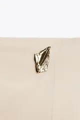 Falda pantalón corta de tiro alto con estampado animal print, cierre lateral oculto y aplique metálico triangular en la parte delantera.