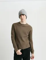 Sweater de punto con textura waffle, color negro, de corte clásico con cuello redondo y mangas largas con puños ajustados.