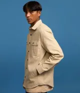 Camisa de manga larga confeccionada en sarga de algodón color verde menta, con cuello inglés y cierre frontal de botones negros. Presenta dos bolsillos de parche con solapa en el pecho y puños con botones.