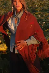 Ruana de tejido rústico en color bordó, con flecos en los bordes y detalles bordados en hilo de colores contrastantes.