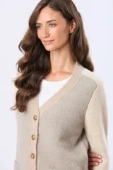 Saco tipo cardigan de tejido grueso con diseño de bloques de color en beige, rosado y blanco. Cuenta con botones frontales y dos bolsillos delanteros.