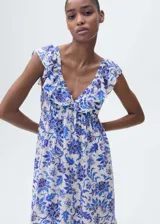 Vestido largo de corte evasé con estampado floral en tonos azules sobre fondo blanco. Presenta cuello de pico, tirantes con volantes y cierre de cremallera lateral.