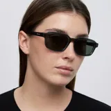 Lentes de sol con montura rectangular de diseño contemporáneo en color gris translúcido y cristales en tono verde oscuro.
