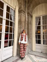 Pantalón de corte recto con estampado de cuadros en tonos rojos, marrones y beige. Presenta un diseño de tiro medio y pernera amplia.