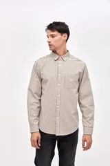 Camisa de corte regular confeccionada en algodón, con diseño de rayas verticales finas en color beige y negro. Presenta cuello clásico, cierre frontal con botones y un bolsillo en el pecho con el logo de la marca bordado.