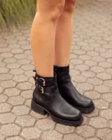Botas cortas de cuero negro con suela track de goma y dos correas con hebillas metálicas ajustables en el tobillo.