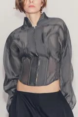 Corset tipo bomber de la colección Zara Woman, confeccionado en hilatura con mezcla de viscosa transparente, con cuello subido, manga larga y varillas interiores que definen la estructura. Cuenta con cierre frontal mediante ganchos metálicos.