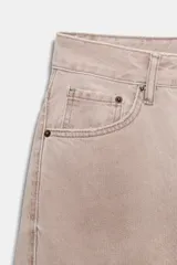 Jeans de tiro medio, color beige rosado con efecto lavado, corte amplio (baggy balloon) y detalle de costuras torcidas en el frente de las piernas.