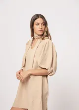 Vestido corto color beige, de corte oversize, con escote en V y mangas globo. Incluye cinturón marrón con hebilla dorada.