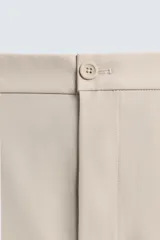 Pantalón de corte regular fit, color negro, confeccionado en tejido elástico. Presenta cintura elástica, cierre frontal con cremallera y botón, bolsillos laterales y bolsillos traseros de vivo.
