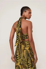 Top negro con estampado de hojas amarillas, escote halter cruzado, corte ajustado y lazo regulable en la espalda.