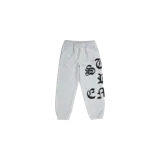 Pantalón de jogging Supreme modelo Cut Out Sweatpant Heather Grey, color gris melange, con cintura elástica con cordón ajustable y puños en los tobillos. Presenta letras negras estampadas con tipografía gótica en la pierna izquierda.
