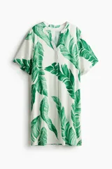 Vestido túnica de corte holgado y largo a la rodilla, con cuello mao y abertura en V. Presenta mangas cortas con hombros caídos, bajo recto con tajos laterales y un diseño ligeramente más largo en la parte posterior.