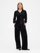 Pantalón de tiro medio y corte recto, confeccionado en terciopelo negro con cintura elástica y bolsillos laterales.